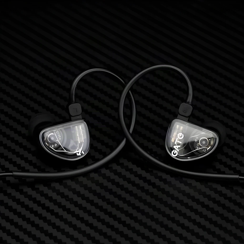 Truthear Gate Auriculares Negro, vista frontal par: carcasa transparente con logo GATE visible sobre fondo texturizado oscuro