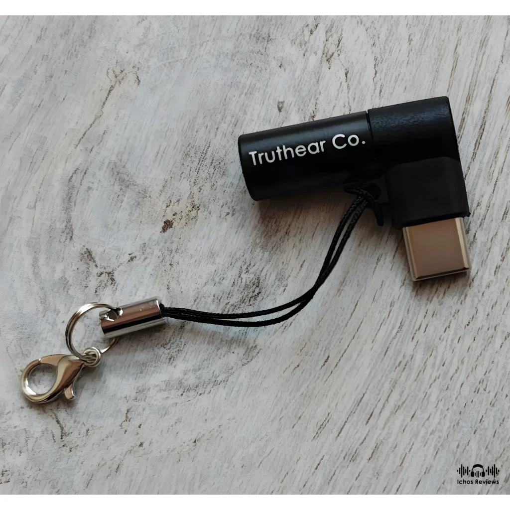 Adaptador DAC USB‑C TRUTHEAR KEYX compacto en negro, con conector metálico, correa de mano y mosquetón plateado; diseño en L con logo Truthear Co.