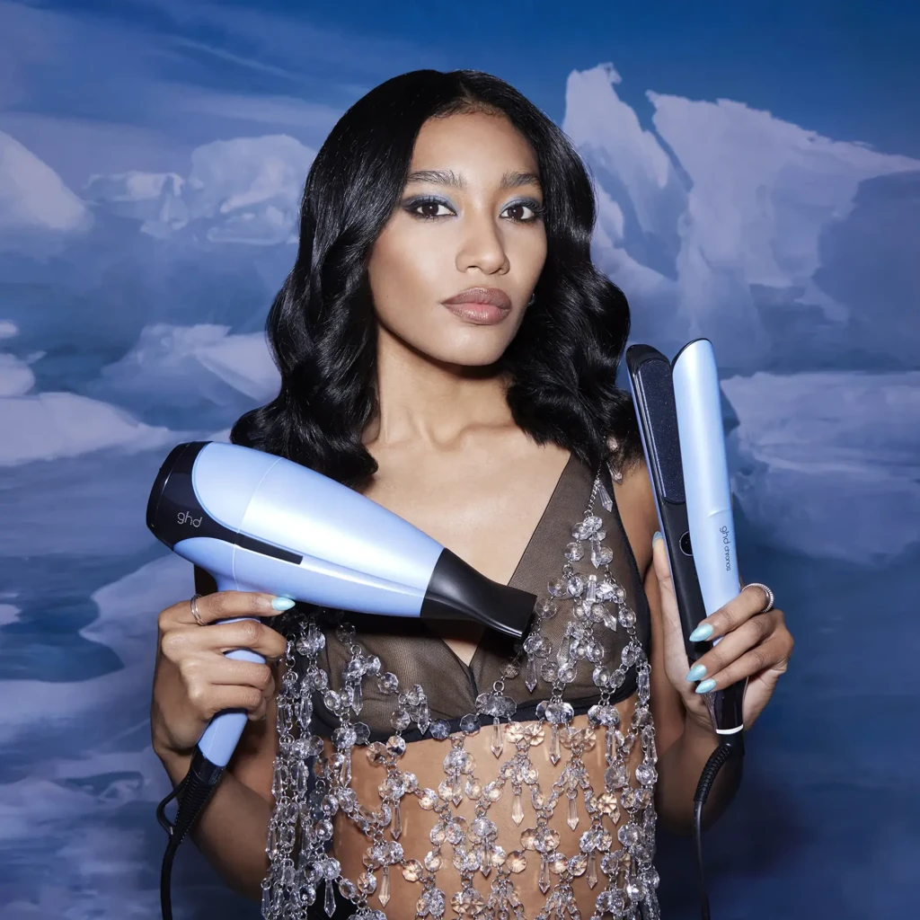 GHD Chronos + Helios Iced Luxe Gift Set azul gélido, lifestyle: modelo segurando chapinha e secador com fundo glaciar