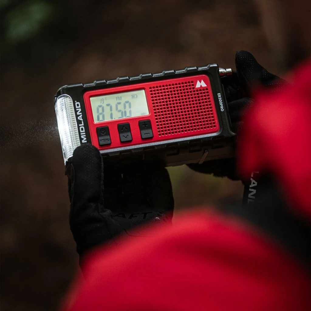 Radio de emergencia Midland ER300 Pro Litio 10000mAh FM Negro, uso exterior: mano enguantada sostiene la radio mostrando