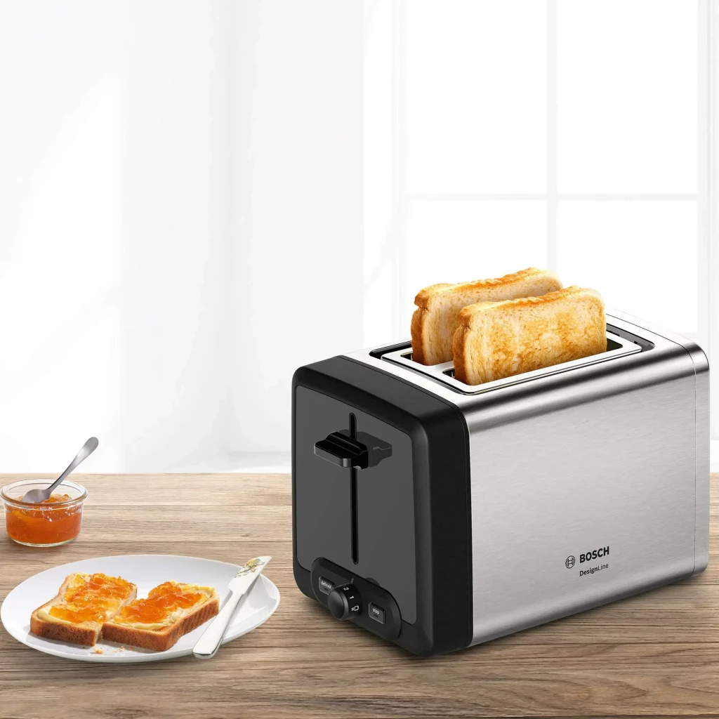 Tostadora Bosch 970W 2 Ranuras Negro/Plata TAT4P420DE, en uso: tostadas doradas en ranuras, mermelada y plato en mesa