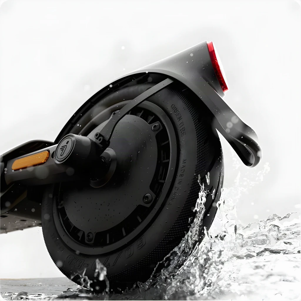 Segway-Ninebot E3 400W negro, detalle rueda trasera: motor hub, neumático sólido y luz trasera roja con salpicaduras de agua