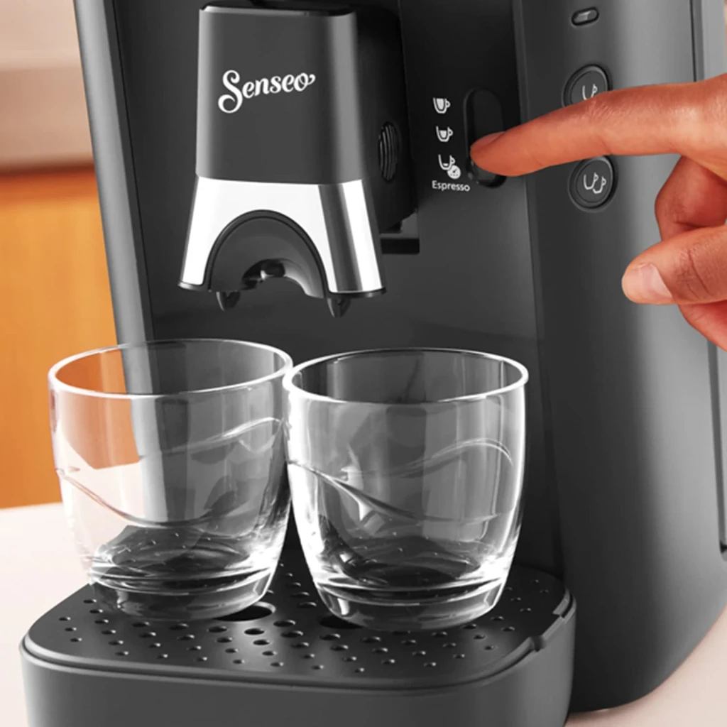 Philips Cafetera Senseo Maestro CSA260/60 noir, détail: doigt appuyant sur le bouton Espresso avec deux verres sous le bec
