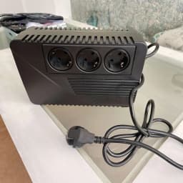 UPS Riello iPlug SE 600VA Linha Interativa 360W Preto, em uso: vista frontal superior sobre mesa, 3 tomadas Schuko e cabo