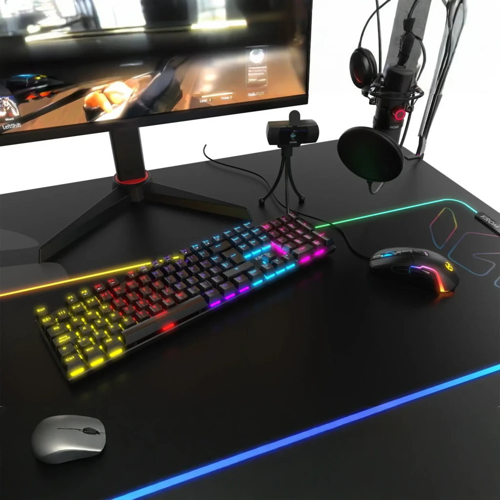 Teclado Gaming Krom Kasic RGB Mecânico Preto, em uso: iluminação multicolor em setup gaming com monitor, rato e microfone