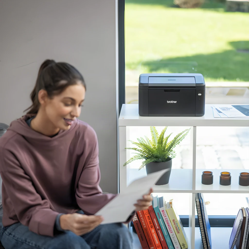 Impressora Brother HL-L1240W Laser Monocromática Preto, em uso: mulher lendo documento impresso ao lado da impressora numa