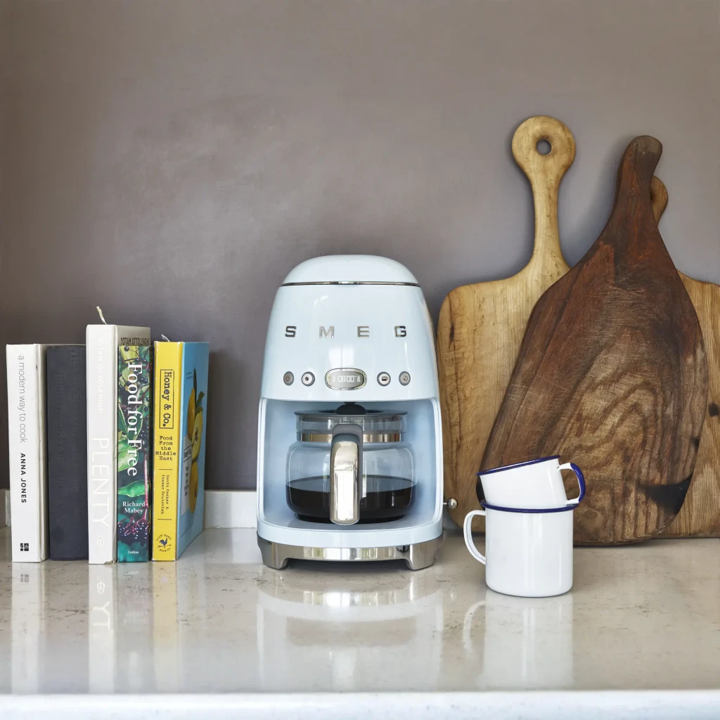 Cafetière filtre Smeg 1,4L 10 tasses 1050W Bleu DCF02PBEU, en utilisation: sur plan de travail en marbre avec livres