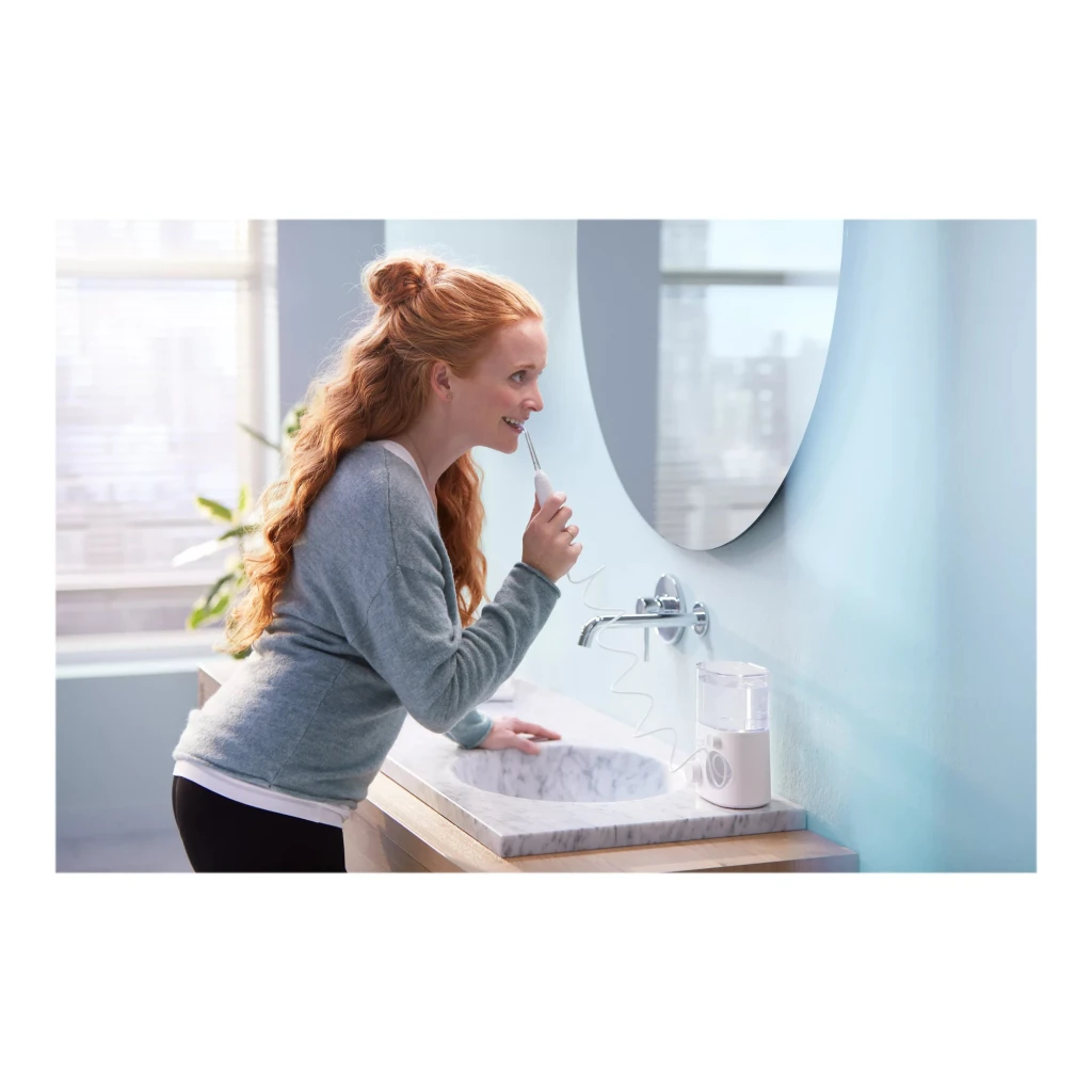 Irrigador dental Philips Sonicare Power Flosser 7000 Sin Cable Batería Blanco HX3911/40, en uso: mujer usándolo ante espejo