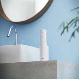 Irrigateur Oral Panasonic EW-DJ66 Sans Fil 60min Blanc, en utilisation: posé sur plan vasque salle de bain avec miroir