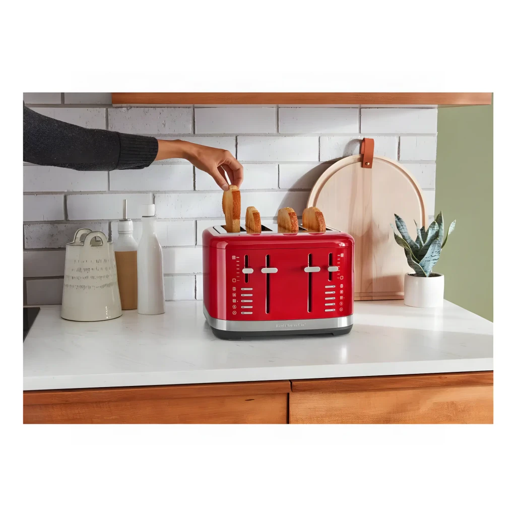 Tostador KitchenAid 1640W 4 Ranuras Rojo 5KMT4109EER, en uso: mano sacando una tostada de las 4 ranuras sobre encimera