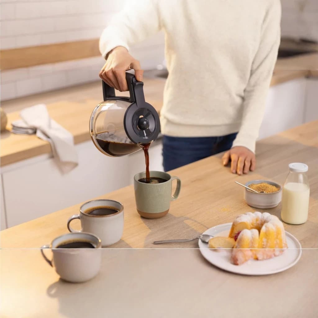 Cafeteira de filtro Bosch MyMoment 1,25L 1200W Branco TKA3M131, em uso: jarra de vidro a servir café em caneca sobre bancada