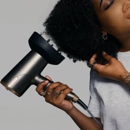 Secador de cabelo Remington ONE Dry & Style D6077 Iónico 2000W Bronze/Cinzento, em uso: mulher a secar cabelo encaracolado