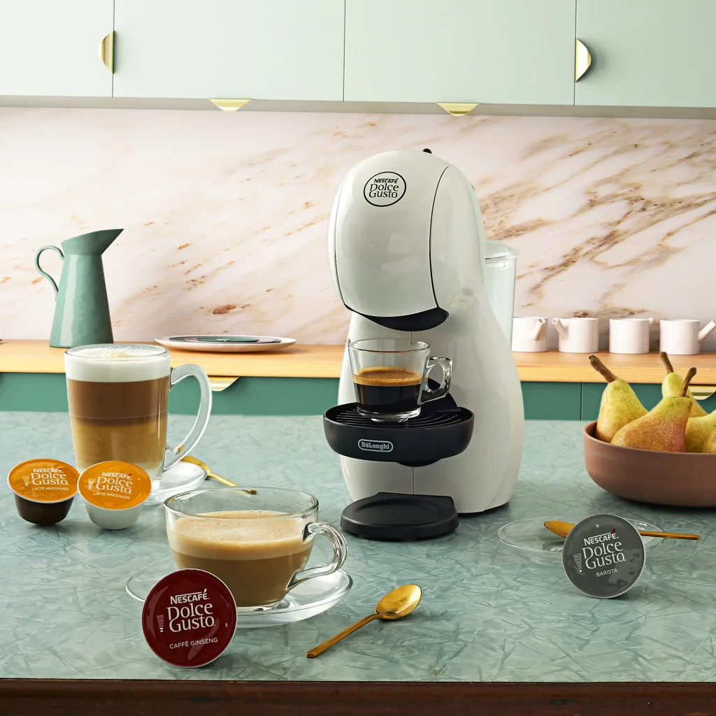 Cafetera de cápsulas De'Longhi Piccolo XS 0,8L Dolce Gusto 15bar Blanco EDG110, en uso: sobre encimera verde con tazas
