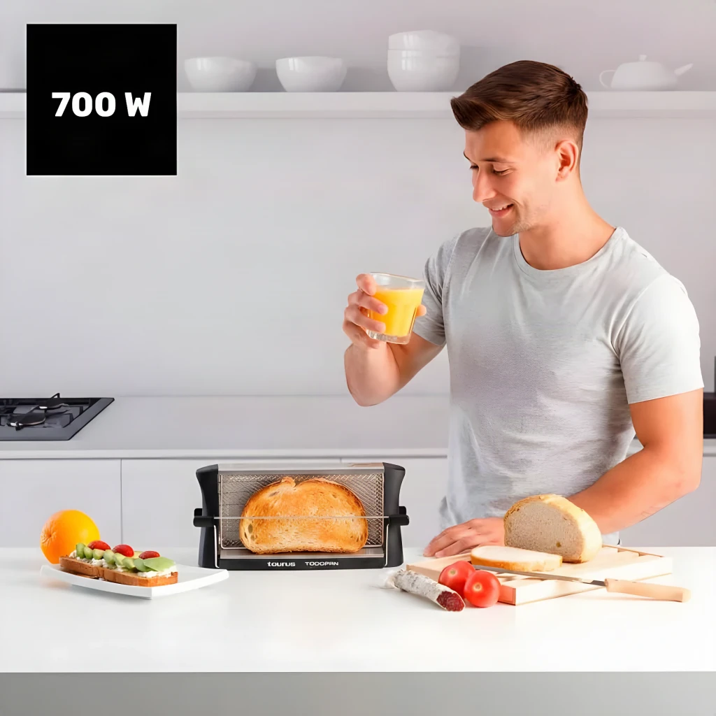 Grille-pain Taurus Todopan 700W 2 Fentes Noir, en utilisation: homme en cuisine grillant du pain avec un jus d'orange
