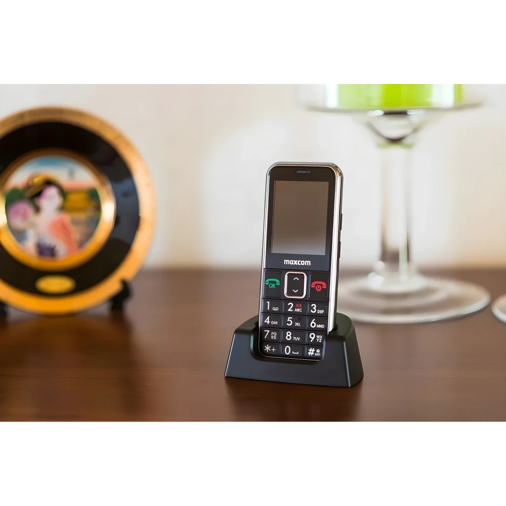 Maxcom Comfort MM730 2,2 pouces Noir 220x176px 2MP 800mAh, en utilisation: téléphone sur socle chargeur sur table avec grand