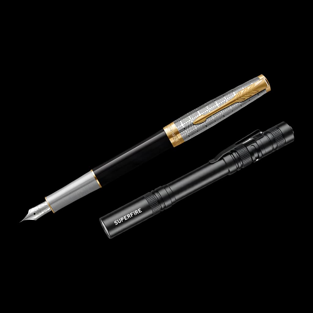 Lanterna LED Superfire L28 Preto 121 lúmens 52 m 5 modos + SOS, detalhe: comparação de tamanho ao lado de uma caneta-tinteiro