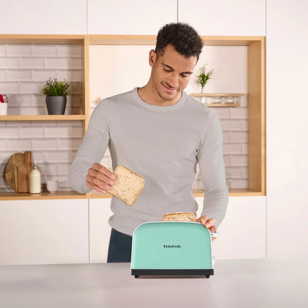 Torradeira Taurus Vintage II 950W 2 Fatias Verde Menta, em uso: homem coloca fatia de pão em cozinha moderna