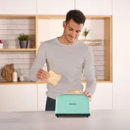 Grille-pain Taurus Vintage II 950W 2 Tranches Vert Menthe, en utilisation: homme insérant une tranche de pain en cuisine