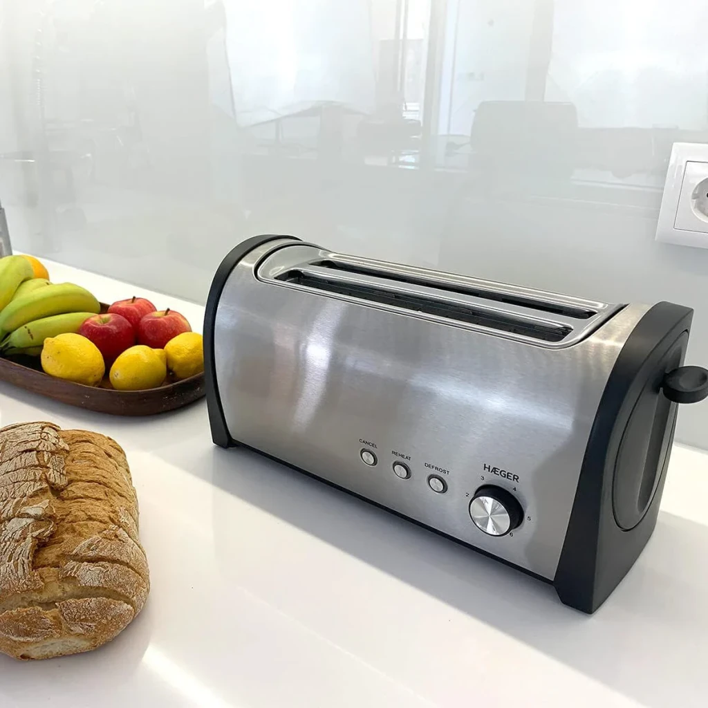 Tostadora Haeger Desayuno Plus 6 1400W 2 Ranuras Negro, en uso: sobre encimera blanca con pan y frutas, cuerpo inox