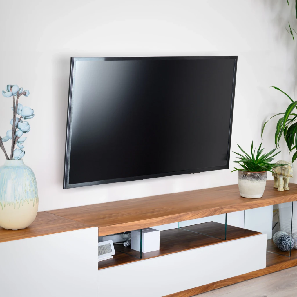 Support TV TooQ Noir Inclinable 32-70 pouces VESA 400x400 LP1071T-B, en situation: grand TV fixé au mur blanc au-dessus d'un