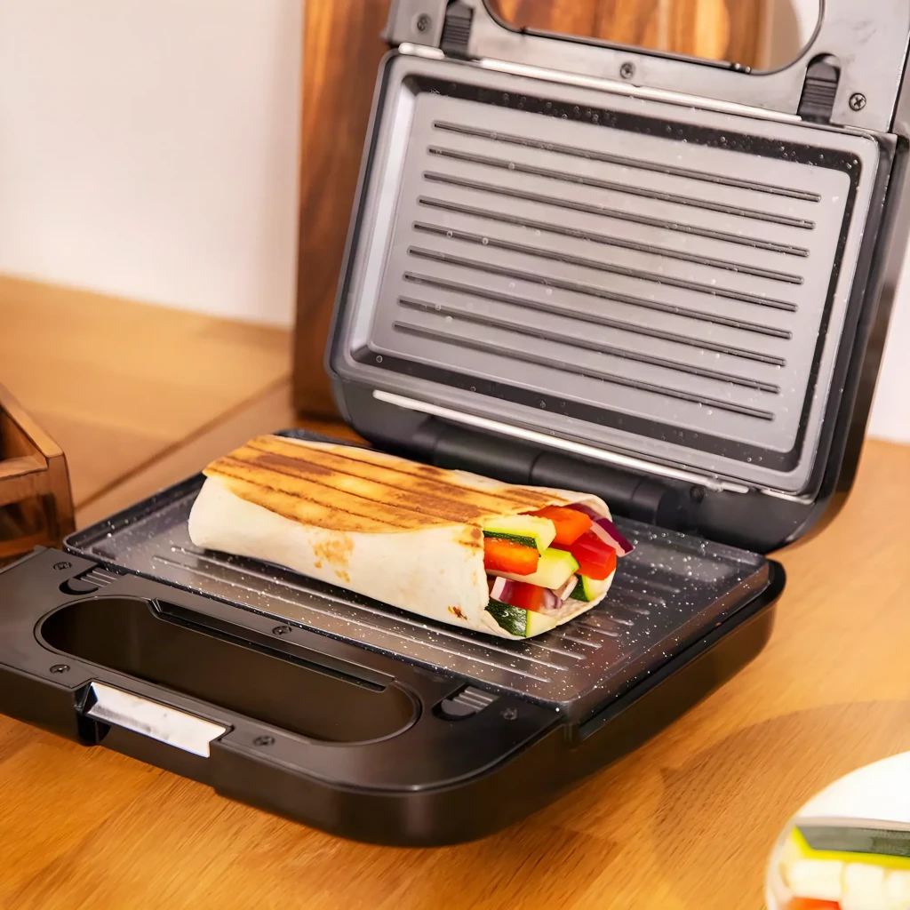 Sandwichera Cecotec Rock'n Toast 4in1 Función Grill y Gofrera 1000W Negro, en uso: abierta con wrap de verduras