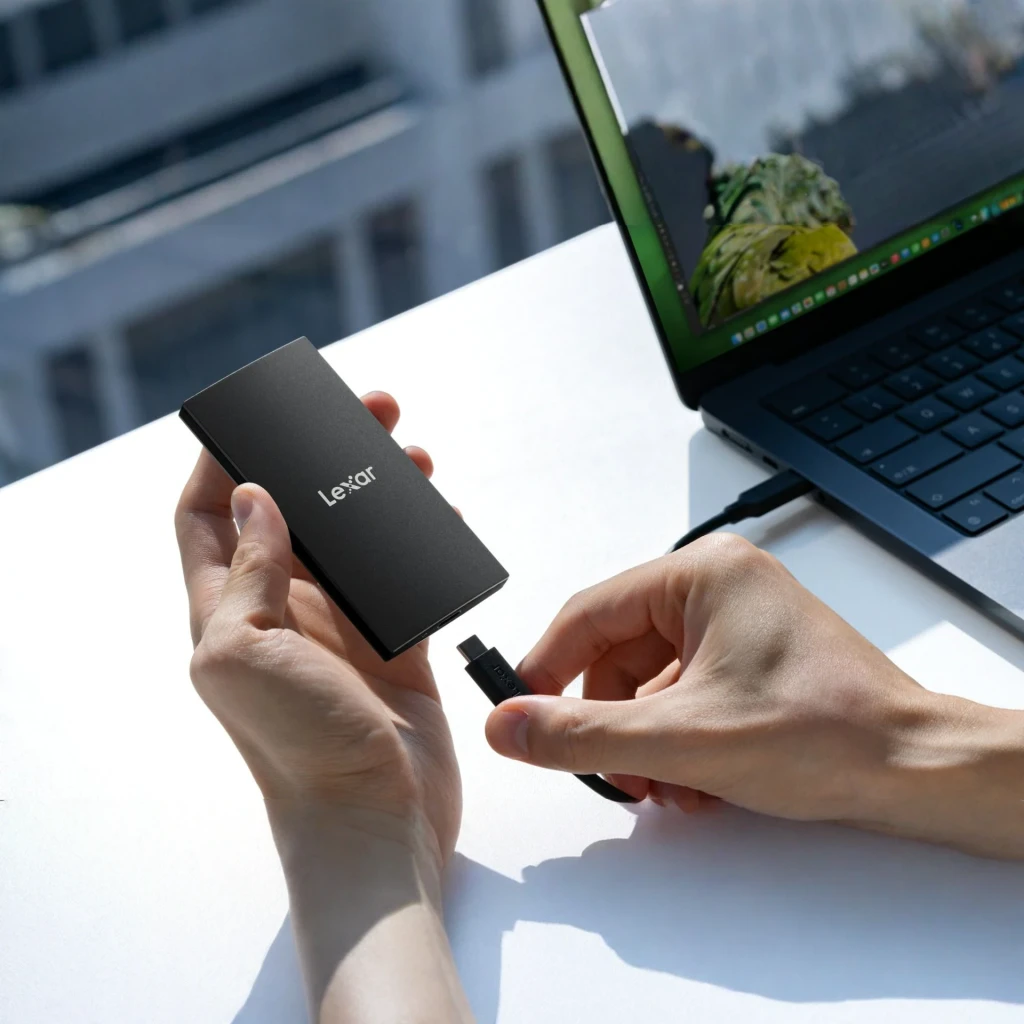SSD Externo Lexar SL300 2TB IP54 USB-C USB 3.2 Gen 2 Preto, em uso: mãos conectando cabo USB-C ao SSD ao lado de um laptop