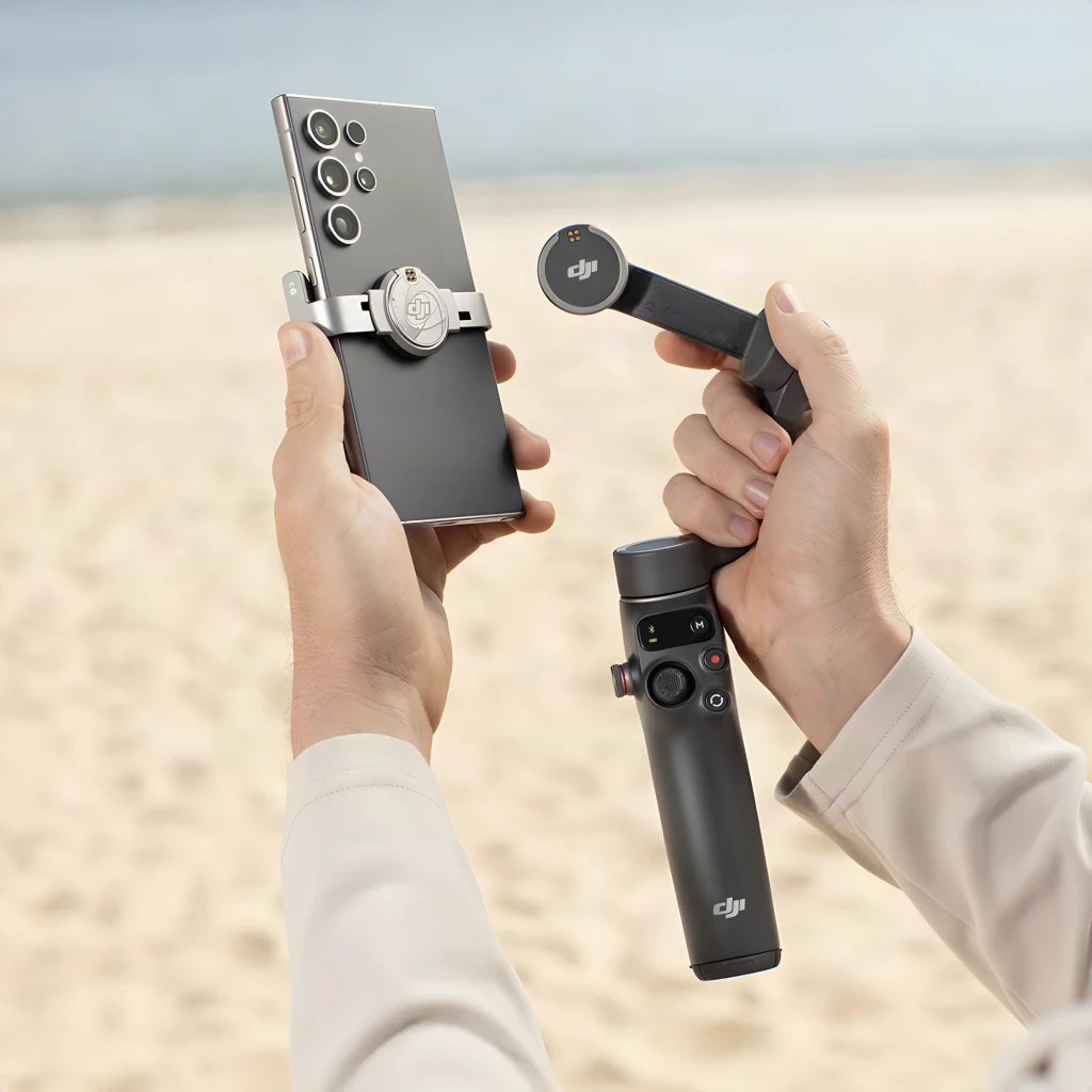 Soporte Magnético DJI para Smartphone Osmo Mobile 7 Gris 170–300 g, en uso: manos acoplando el soporte al gimbal en la playa