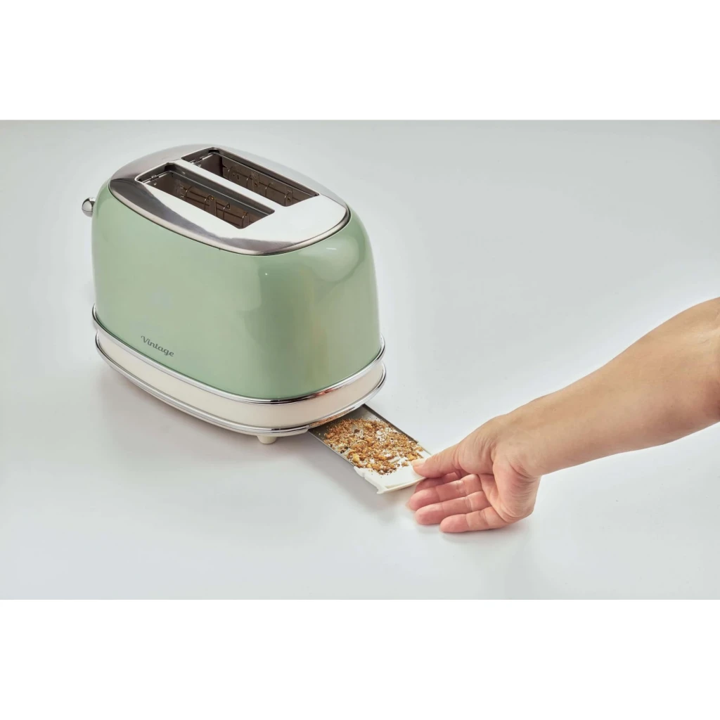 Torradeira Ariete Vintage 155 810W 2 Ranhuras Verde, em uso: mão a retirar o tabuleiro de migalhas com resíduos de pão