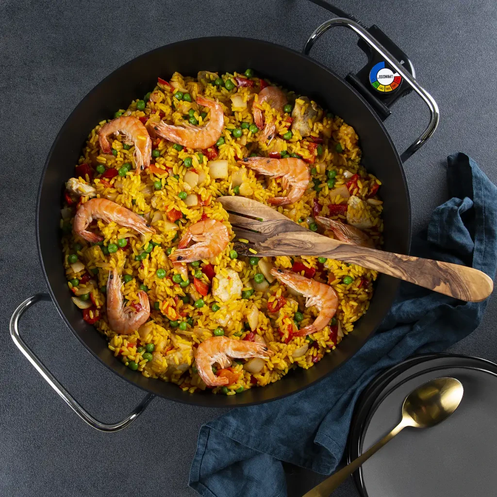 Sartén eléctrica Princess Multi Wonder Chef Pro 5,4L 1800W Negro, en uso: paella con gambas y verduras, cuchara de madera