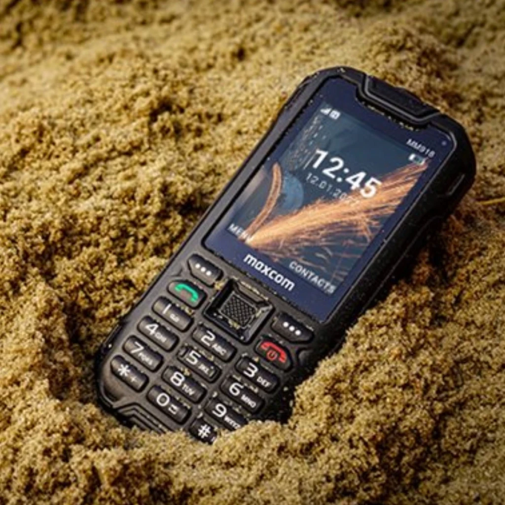 MaxCom Strong MM918 4G VoLTE Preto IP68 2500mAh 2.4 polegadas, em uso: vista frontal semi-enterrado na areia, ecrã aceso