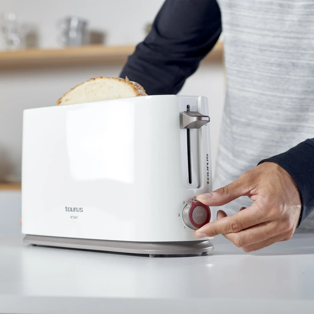 Tostadora Taurus My Toast 1000W 1 Ranura Blanco, en uso: mano ajustando el dial de tostado con pan en la ranura