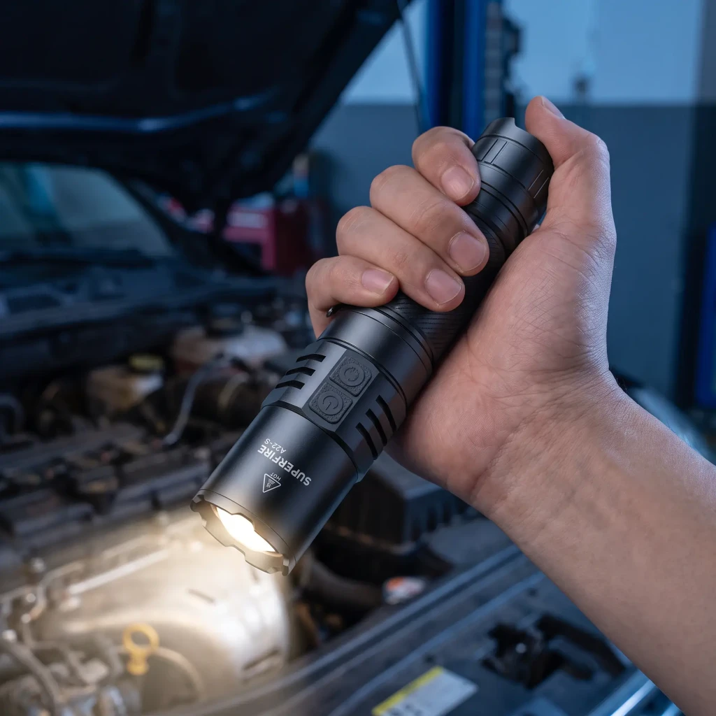 Lanterna LED Superfire A22S Preto USB-C 2300 lúmens 300 m em uso: mão segura a lanterna acesa iluminando motor de carro