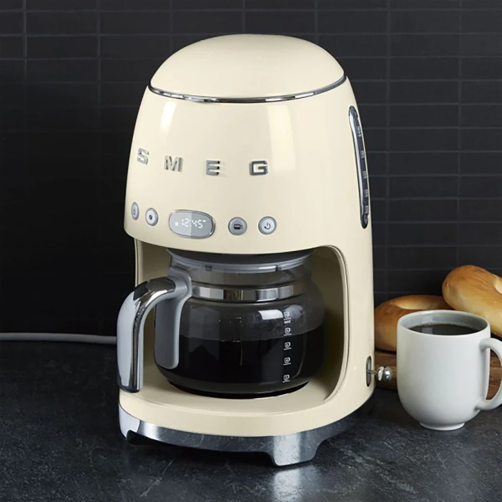 Cafetière filtre SMEG 50's Style 1,4L 1050W Crème DCF02CREU, en utilisation: vue de face sur plan de travail sombre