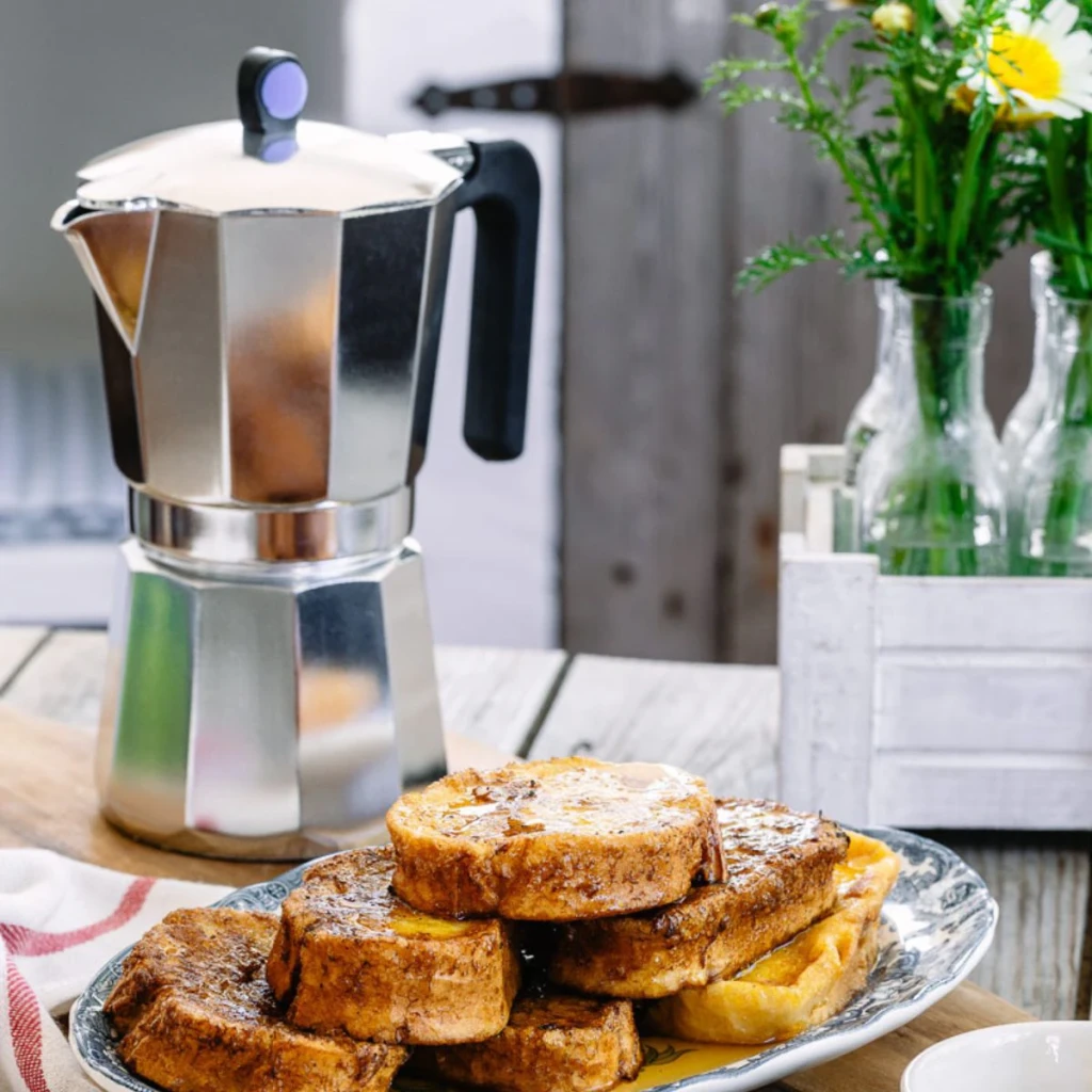 Cafetera italiana Monix Induction Express 6 Tazas Plata M860006, en uso: sobre mesa de madera con torrijas en primer plano