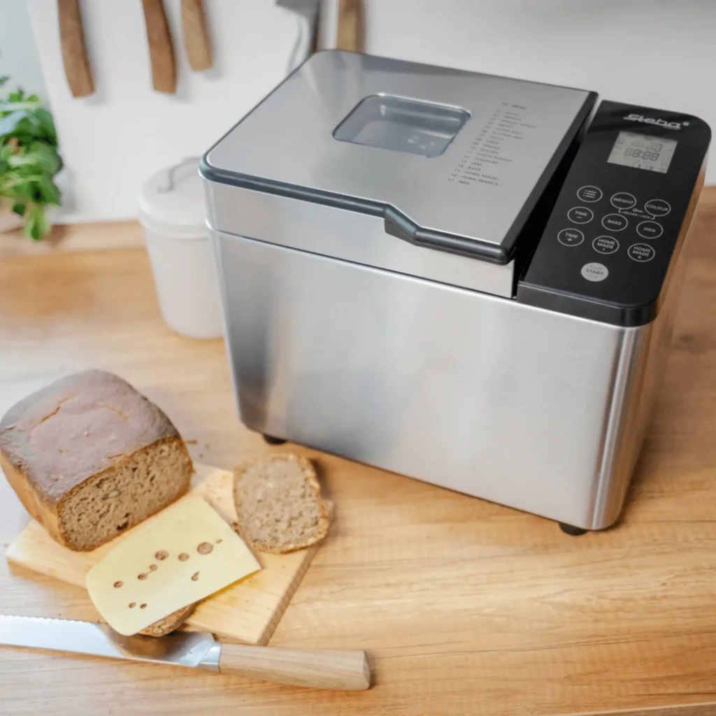 Machine à pain Steba BM 2 600W jusqu'à 1000g Acier Inoxydable/Noir, en utilisation: sur plan de travail bois avec pain frais
