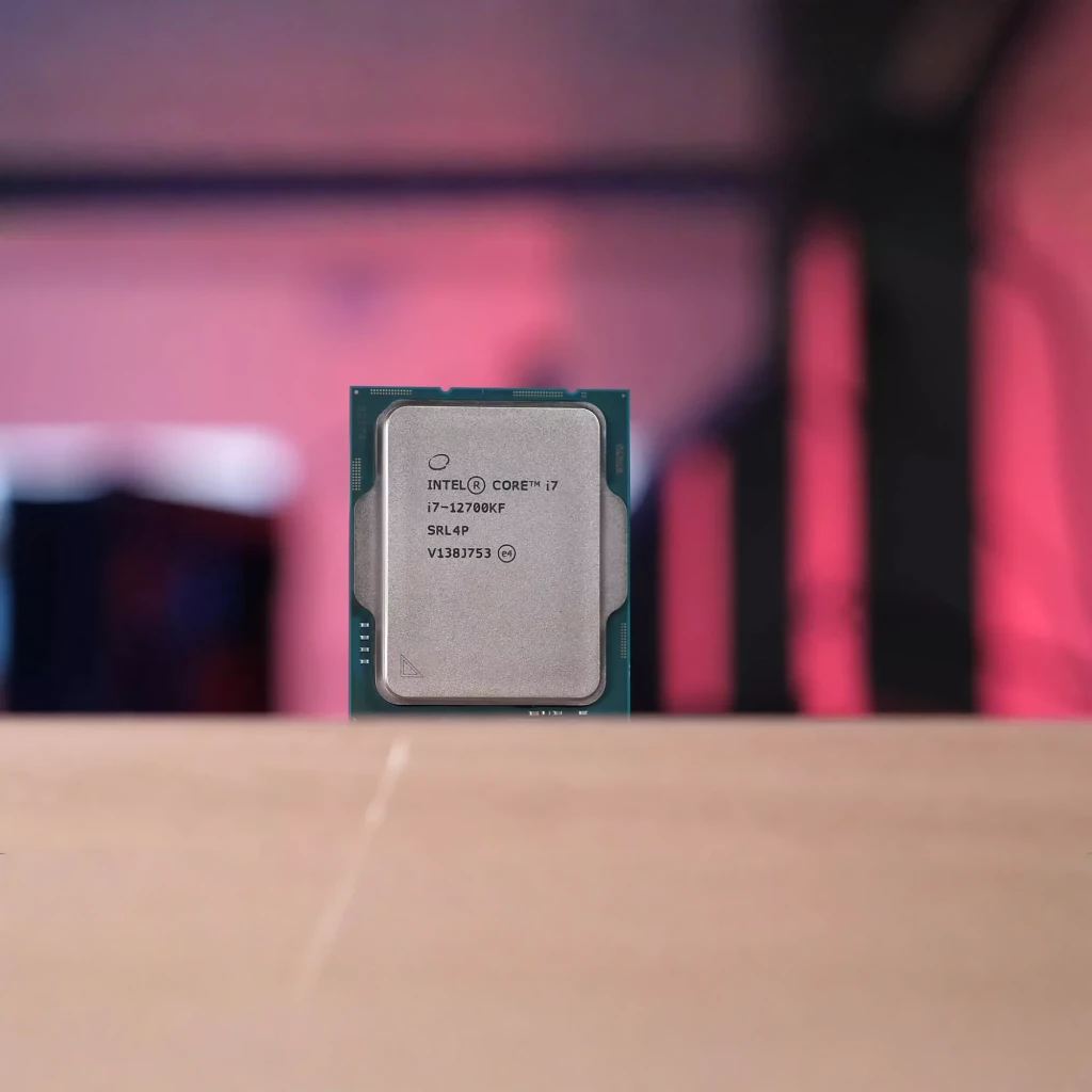 Intel Core i7-12700KF Tray 12 Cœurs LGA1700, en utilisation: IHS métallique gravé i7-12700KF sur surface en bois, fond rose