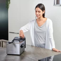 Friteuse Taurus Professional 3 Plus 3L 2100W Acier Inoxydable, en utilisation: femme ajustant le couvercle sur un plan