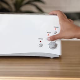 Grille-pain Haeger Bulgari 6 1000W 1 Fente Blanc, en utilisation: main appuyant sur Reheat avec voyants allumés et molette 6