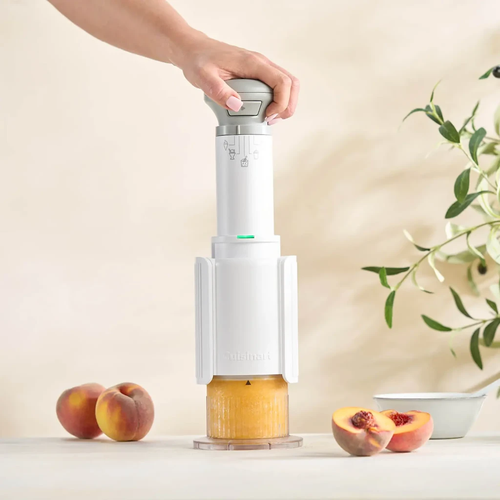 Machine à glace Cuisinart 0,24l Blanc ICEFD10E, en cours d'utilisation: main tenant le moteur sur bol avec pêches