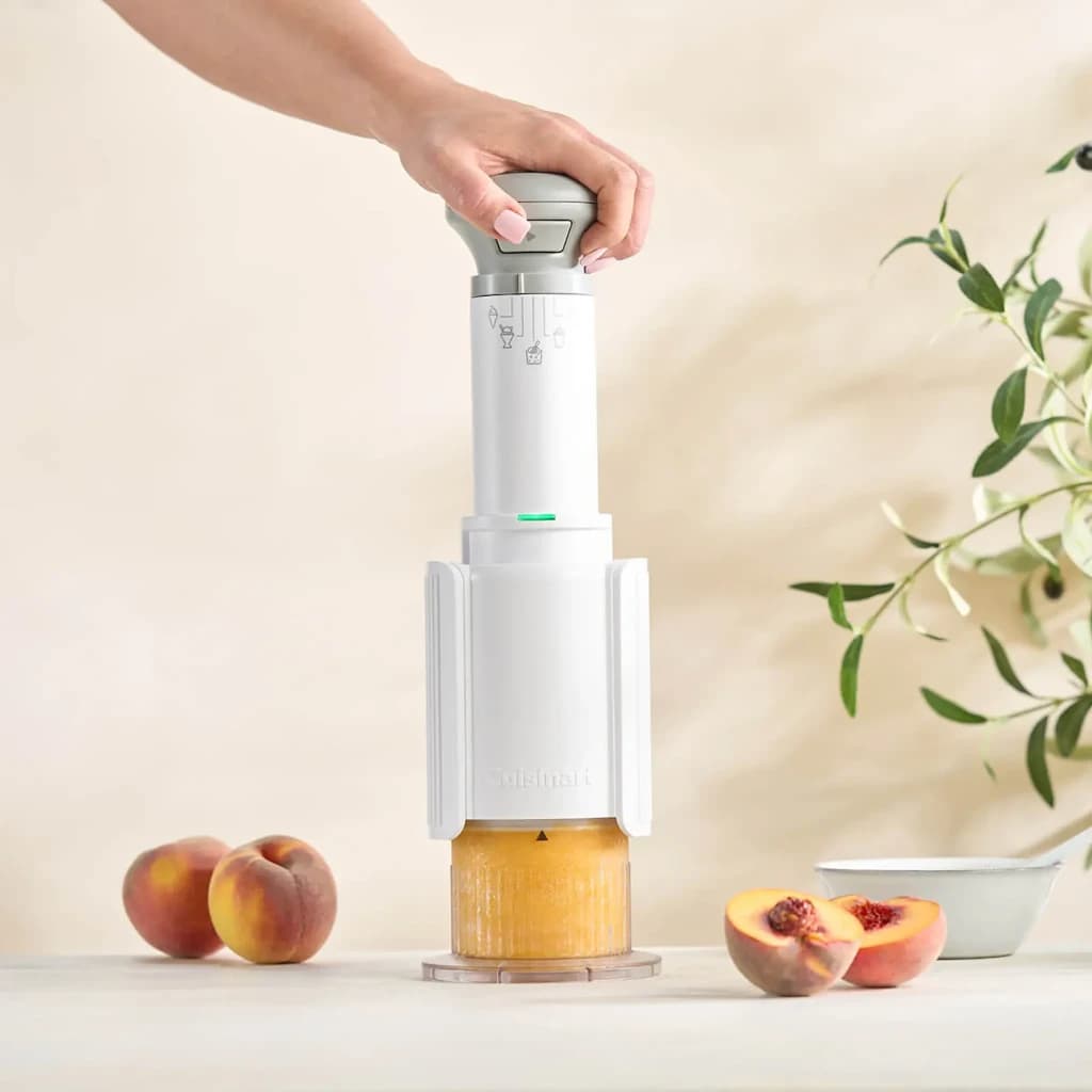 Machine à glace Cuisinart 0,24l Blanc ICEFD10E, en cours d'utilisation: main tenant le moteur sur bol avec pêches