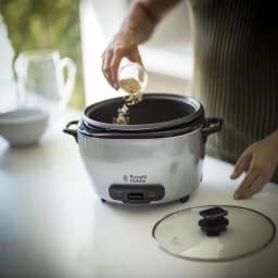 Cuiseur à riz Russell Hobbs Maxicook 5L 1000W Noir/Acier Inoxydable 23570-56, en cours d'utilisation: main versant du riz
