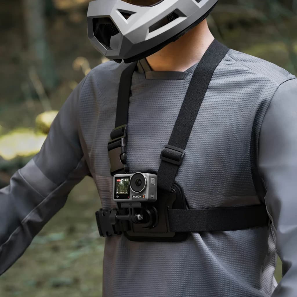 Suporte de peito DJI Osmo Action Chest Strap Mount Preto, em uso: ciclista com capacete usa arnês preto com câmara Action 3