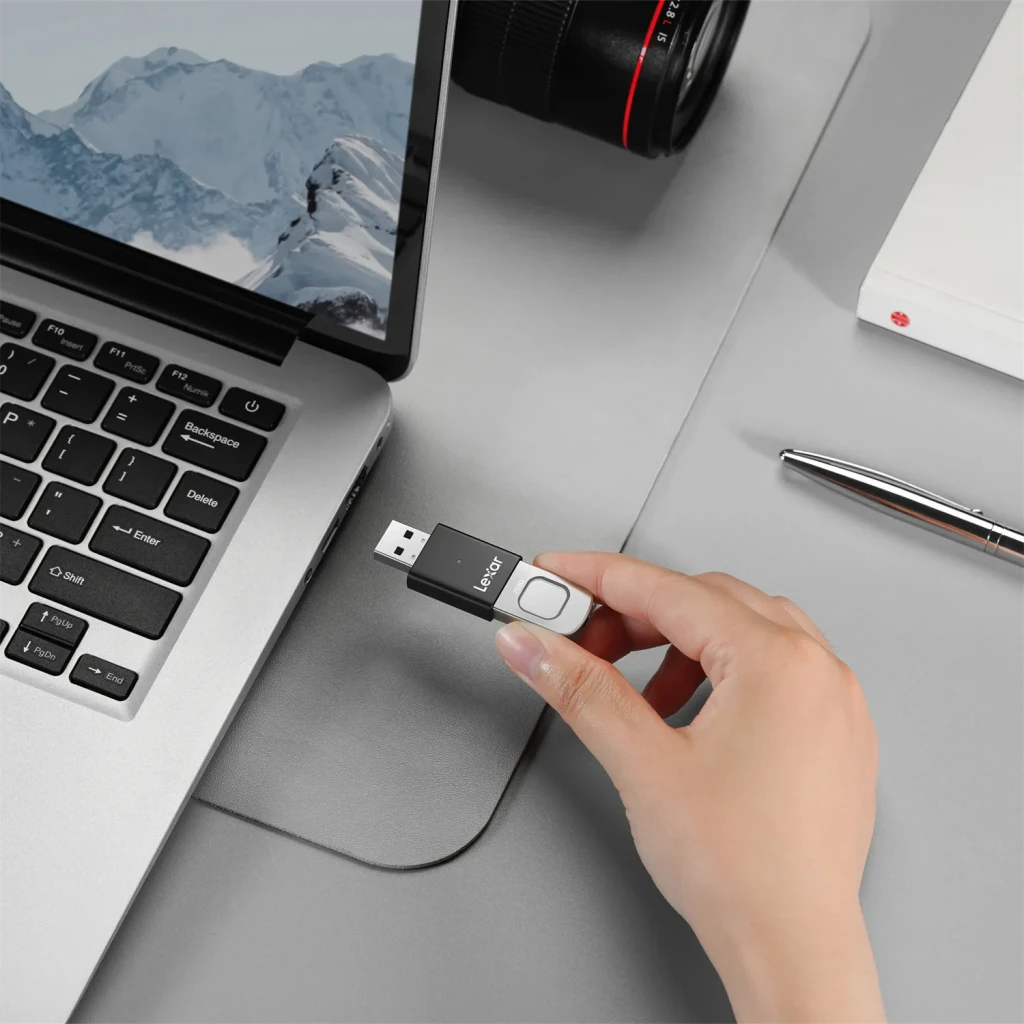 Clé USB Lexar JumpDrive Fingerprint F35 Pro 128Go USB 3.2 400 Mo/s Noir, en utilisation: main branchant la clé sur le port
