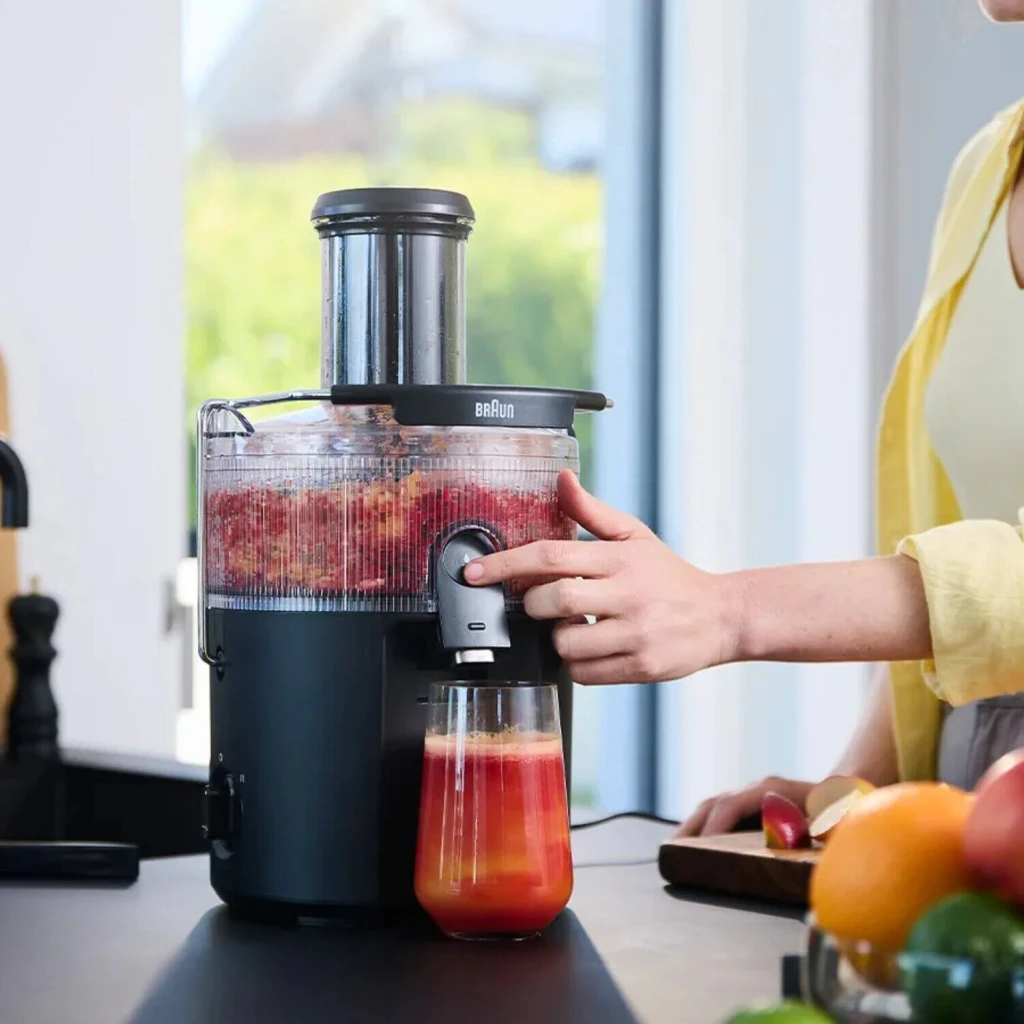 Centrifugeuse Braun MultiJuice 5 SJ5000 800W 2L jus Noir, en utilisation: femme pressant des fruits rouges, verre de jus