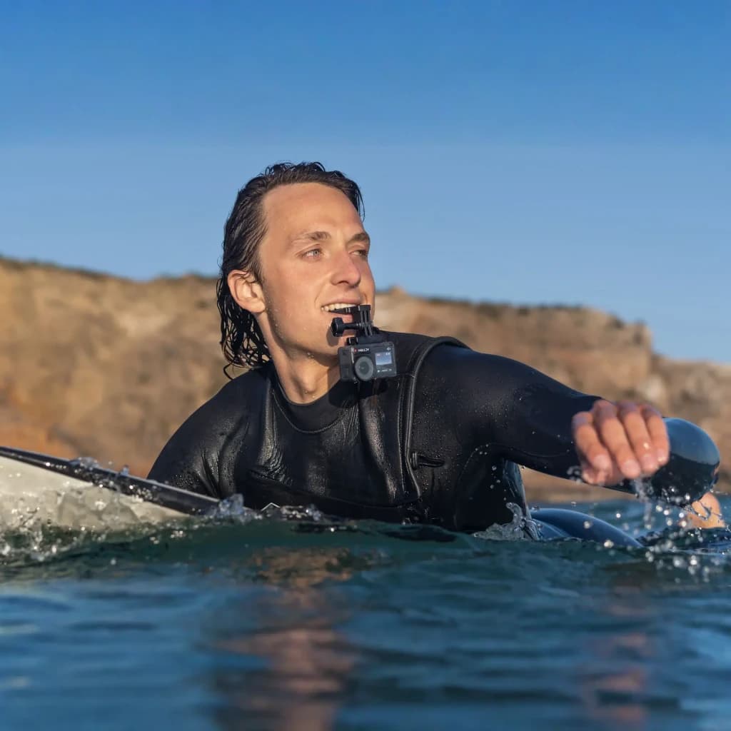 Suporte de Mordida DJI Osmo Action Bite Mount Preto, em uso: surfista de fato preto morde o suporte com câmara no mar