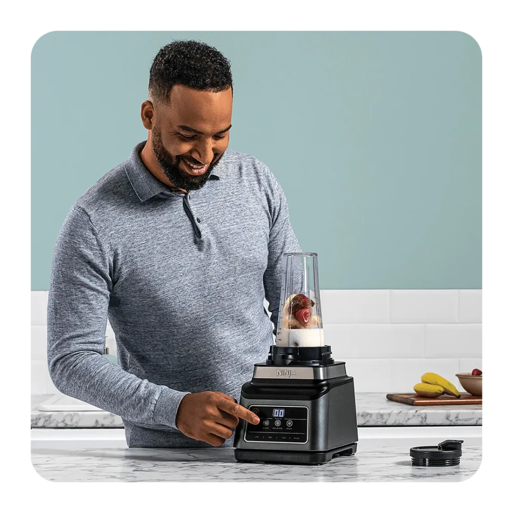 Liquidificador Ninja 2,1L 1200W 3 velocidades Preto BN750EU, em uso: homem pressiona painel tátil em bancada de mármore