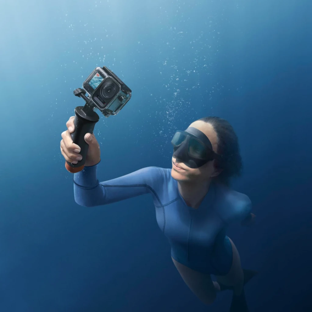Kit Accessoires Plongée DJI Osmo Action 3 Noir 60 m IP68, en utilisation: plongeuse en combinaison bleue tient la caméra