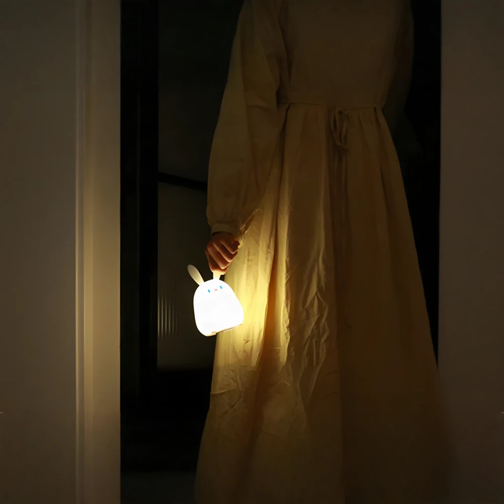 Veilleuse Enfant Superfire Little Rabbit Blanc RAB-02, en utilisation: main tenant la veilleuse allumée éclairant une robe