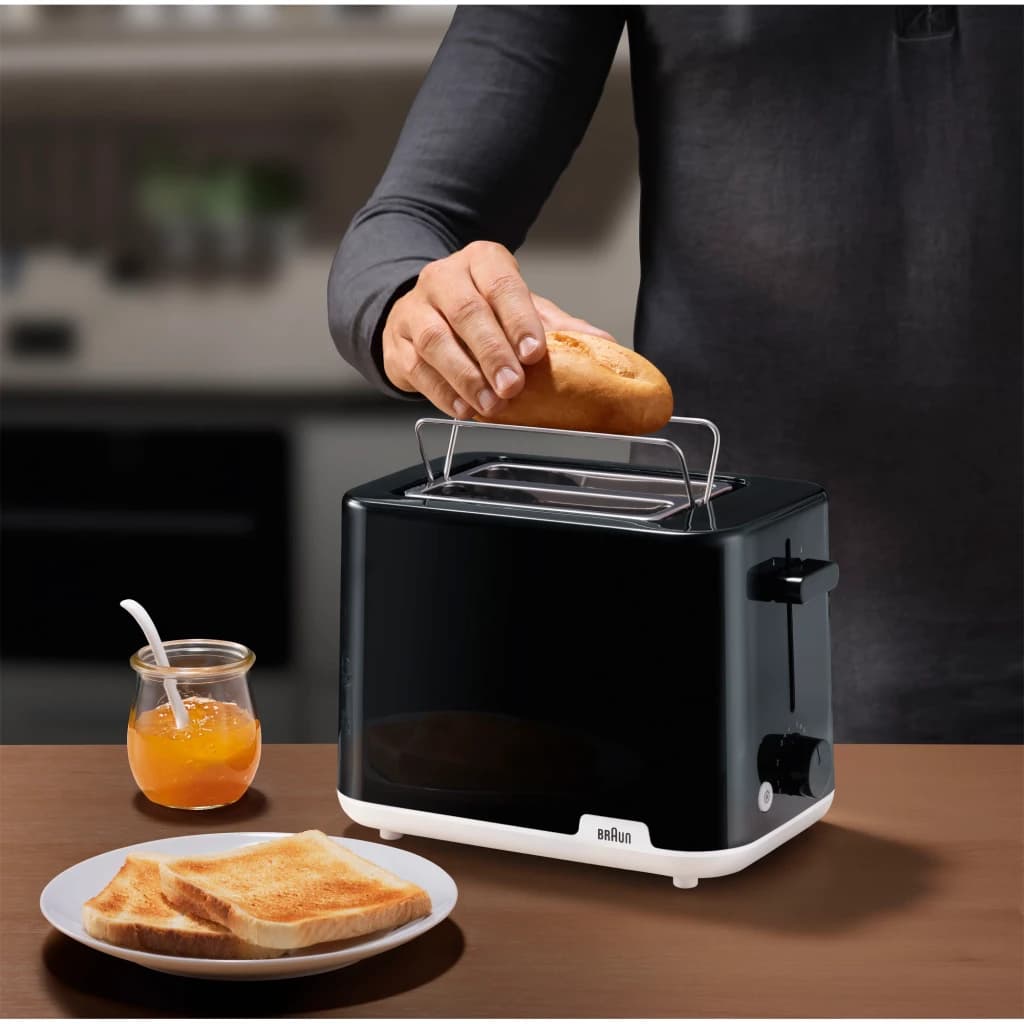 Torradeira Braun HT 1010 900W 2 Ranhuras Preto, em uso: mão a inserir pão na ranhura, torradas e compota sobre a mesa