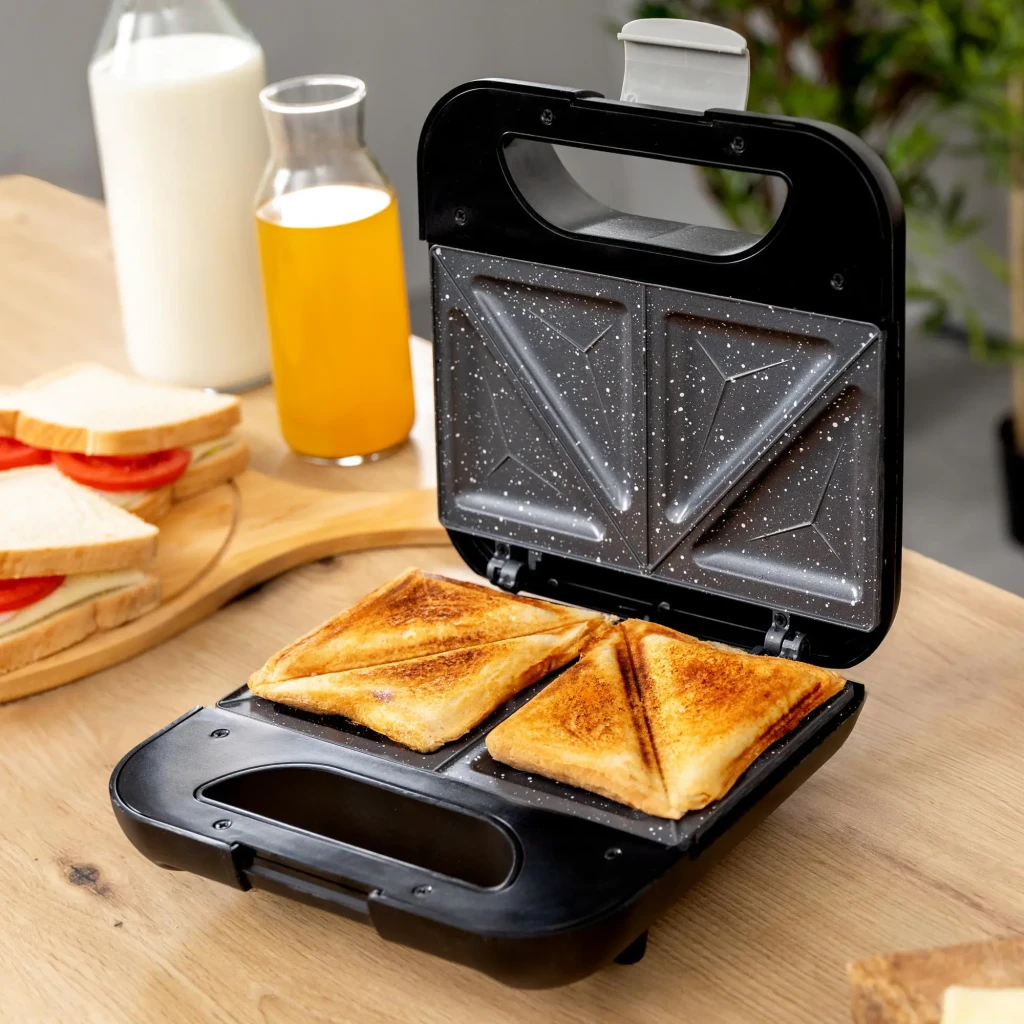 Sandwichera Cecotec Rock'nToast Classic+ 800W 2 bocadillos Acero inoxidable/Negro, en uso: abierta con 2 bocadillos tostados